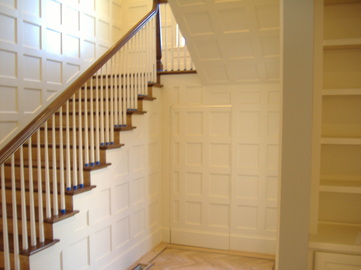 This staircase is referred to as an over-the-post system. It has a double starting step, with over-sized volutes. The part of the rail that curves to get up over the newel post is referred to as a gooseneck, or up-easing. The balusters are wrought iron, with different designs alternating. Installation included all skirtboards, risers, aprons, nosings, mouldings, and complete balustrade.